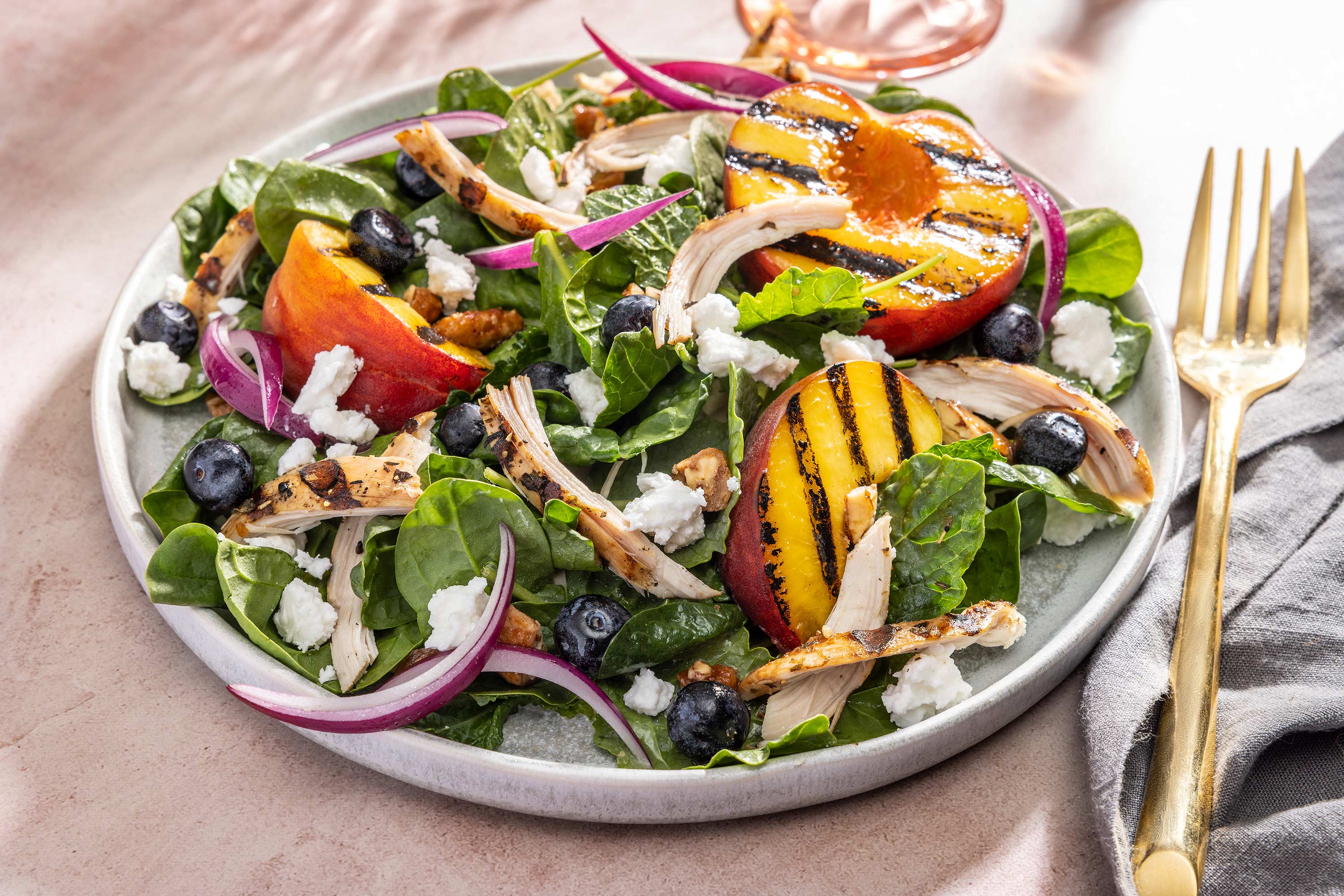 Grilled peach summer salad with feta and red onions shot at 3/4 angle.