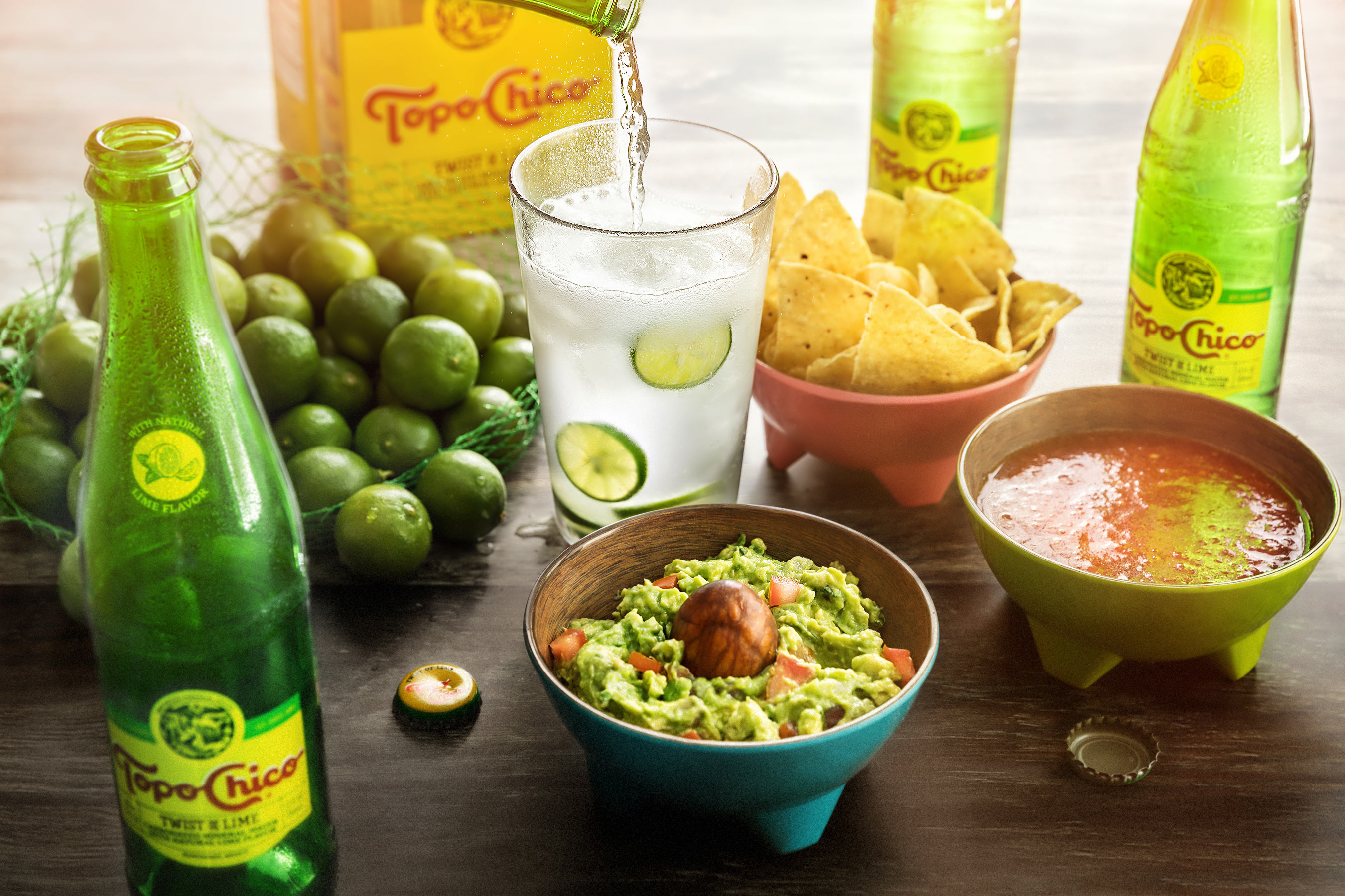 Glanger Photography | Pouring a glass of Topo Chico with bottles, guacamole, limes, chips & salsa