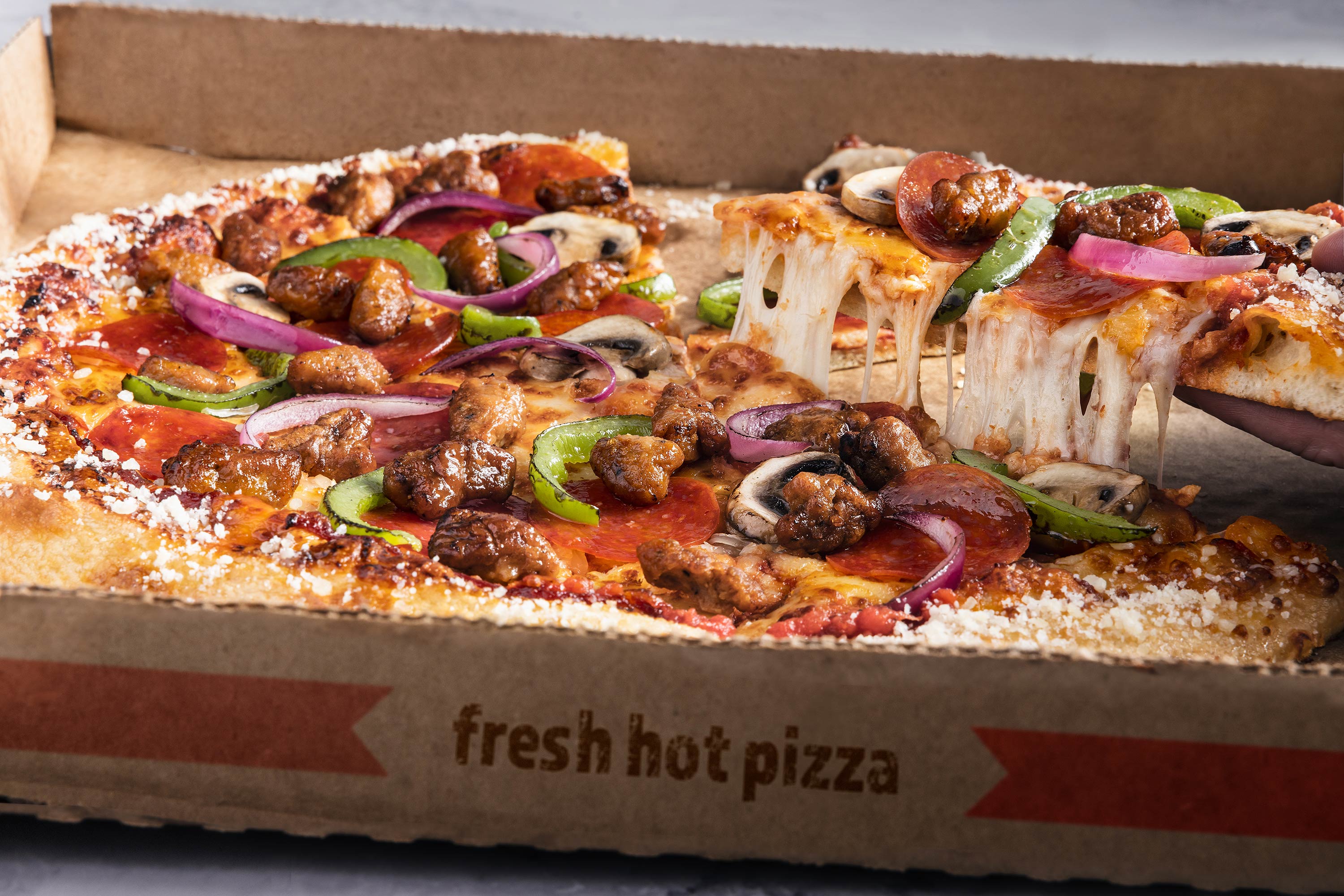 Glanger Photography | Meat lovers pizza with sausage, pepperoni, green peppers and red onions.  Slice is being lifted with a cheese pull. 