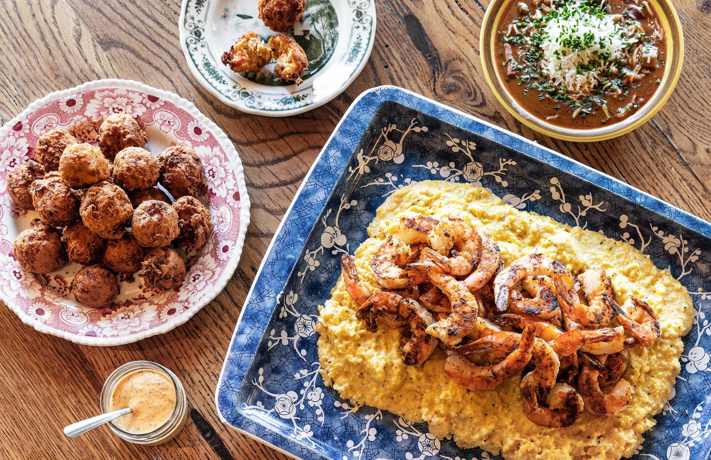 Glanger Photography | Blue platter of shrimp on rice with hush puppies + beans on a wood surface